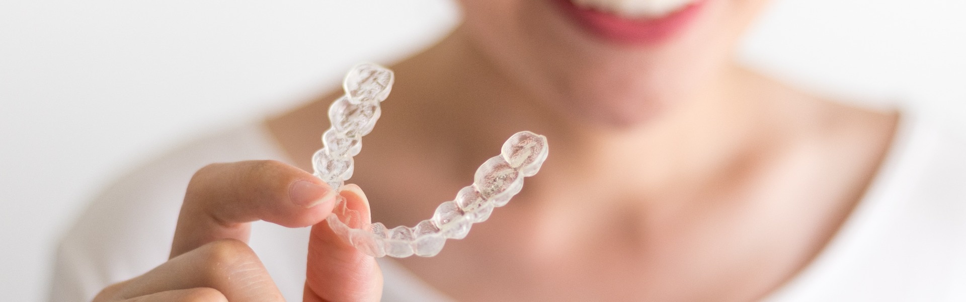 A smiling woman holding invisalign or invisible braces orthodontic equipment jpg