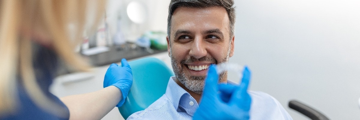  Zahnärztin zeigt einem Patienten in Zahnklinik Invisalign Klammer, Zahnuntersuchung und das Konzept Gesunde Zähne