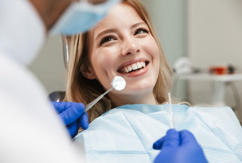 Image of pretty woman sitting in dental chair while professional doctor fixing her teeth