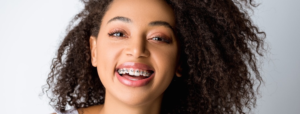 Lachendes afroamerikanisches Mädchen mit Zahnspange, isoliert auf g